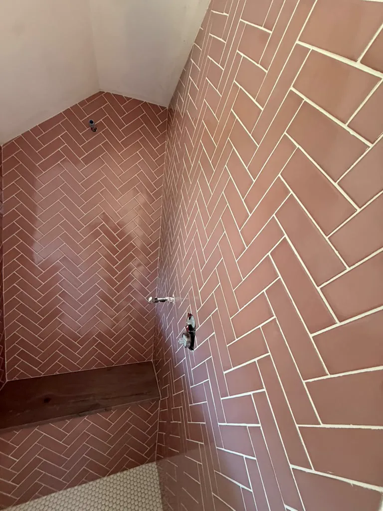 Shower with brown herringbone tile and a built-in bench
