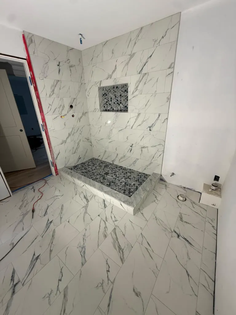 Marble tile bathroom with corner shower and pebble pan