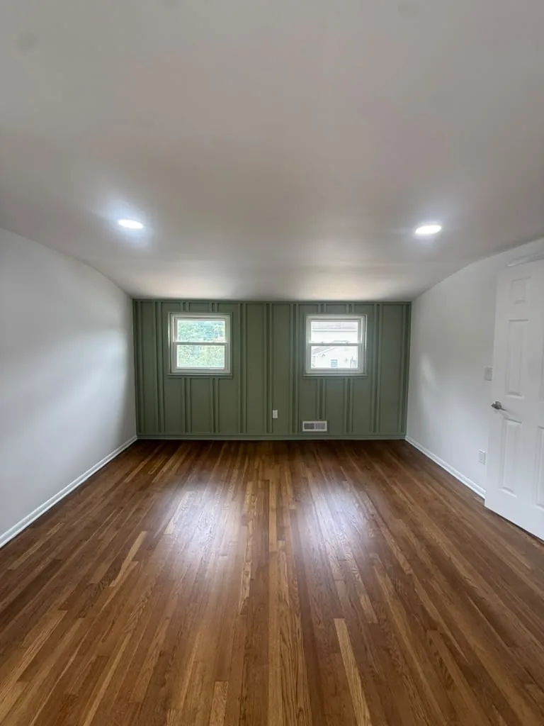 Room with sage green accent wall and refinished hardwood floors